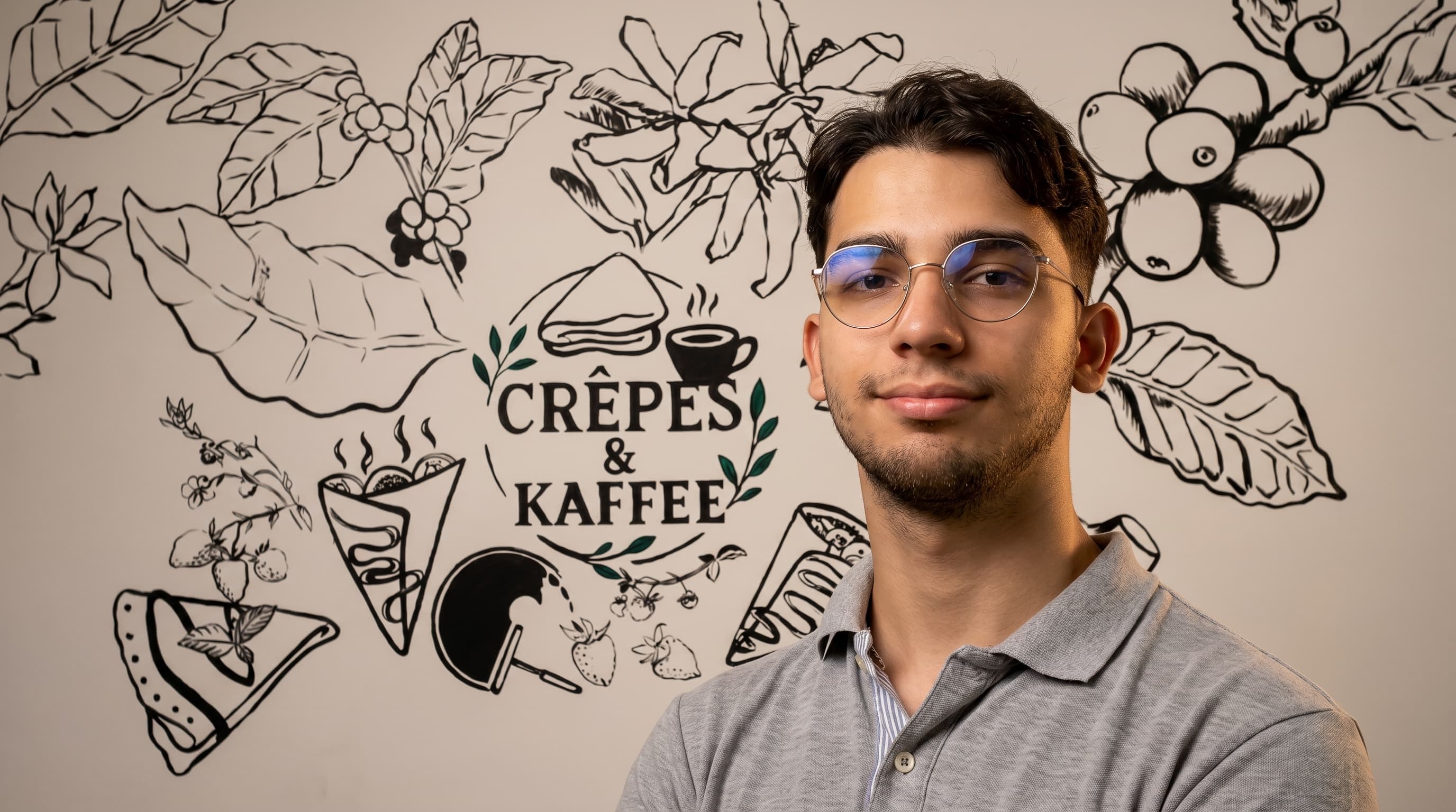 Kevin Alexander Marín frente al mural de Crepes & Kaffee